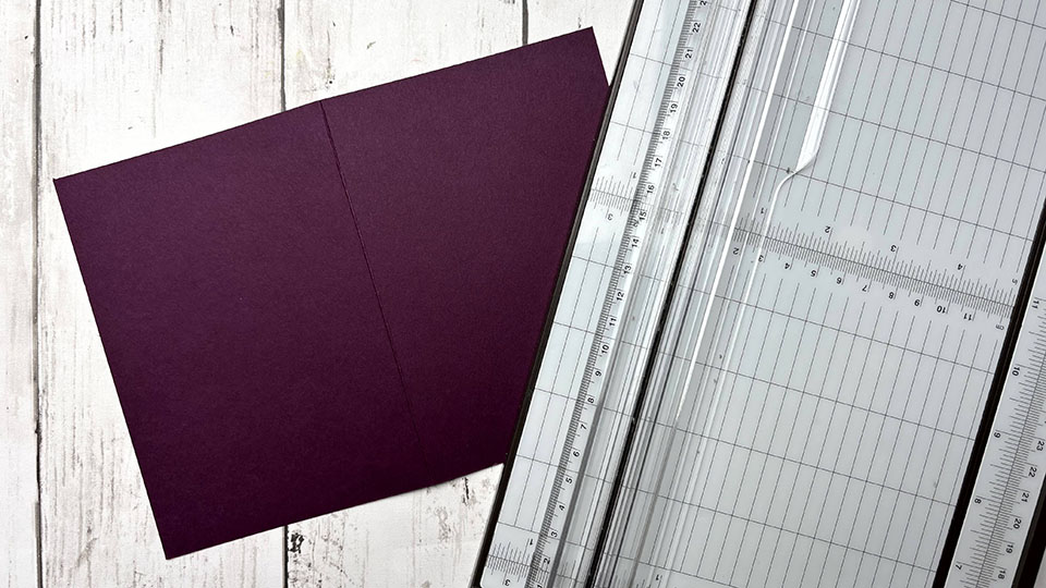 Découpe du carton aubergine au coupe-papier pour réaliser le fond d'une carte anniversaire graphique scrapbooking