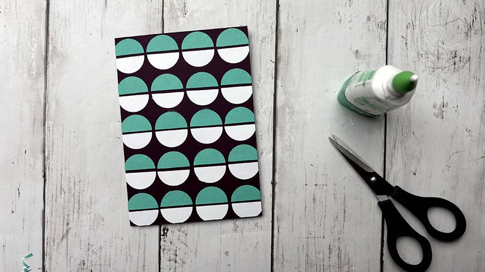 Découpe des demi-cercles qui dépassent du bord de la carte scrapbooking graphique homme avec ciseaux