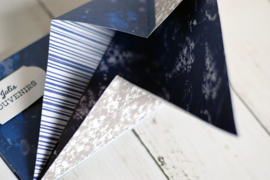 Gros plan sur le pli en diagonale d'une page de mini-album origami — papiers Stampin Up bleu nuit et rayures