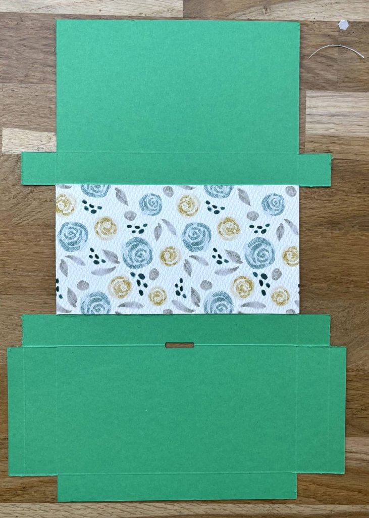Colle un morceau de papier à motifs de 15x8 cm dans la partie centrale. Ce sera le fond de la boîte.