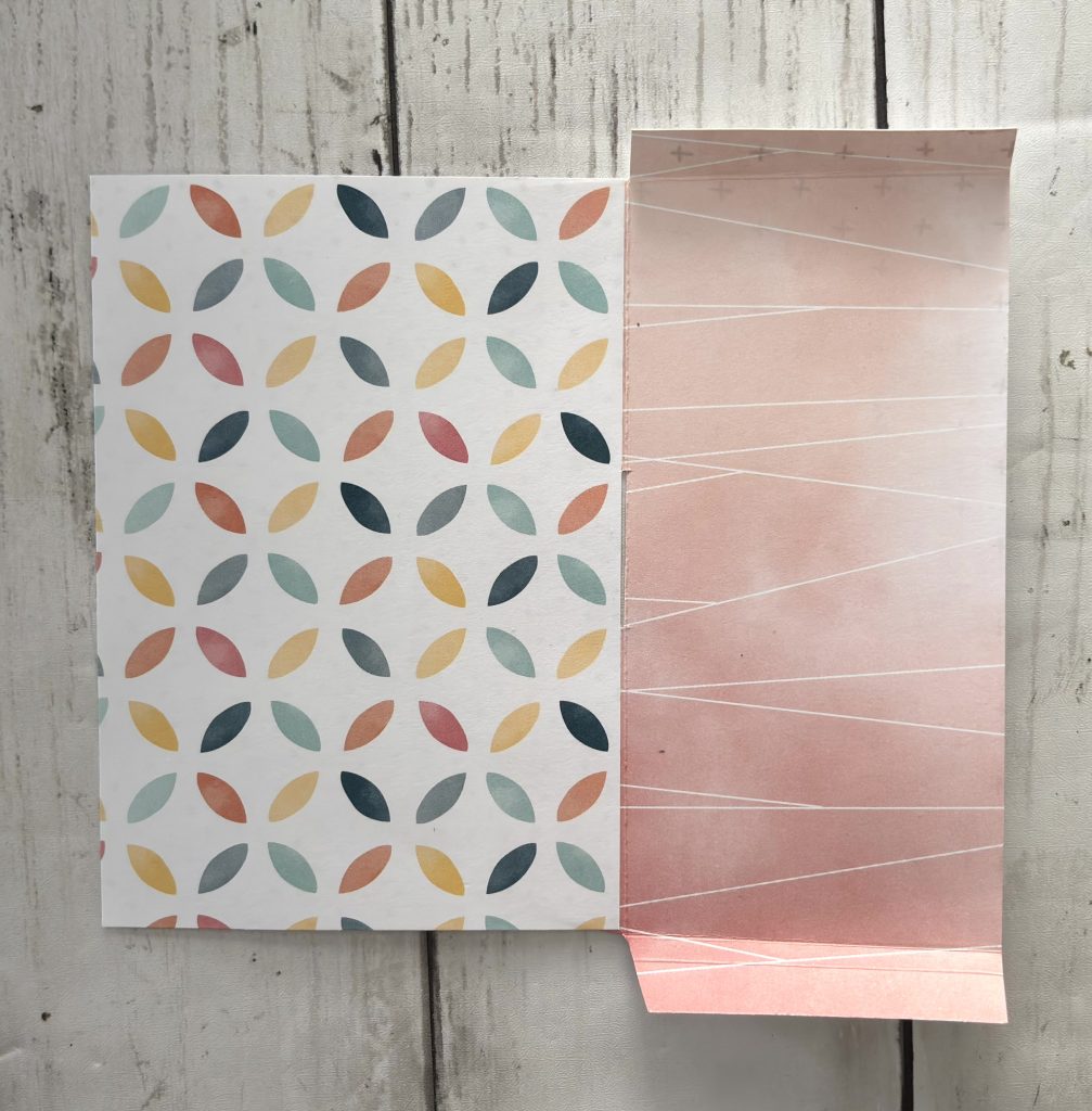 Papier à motif feuilles multicolores et papier rose pliés pour le mécanisme de la carte