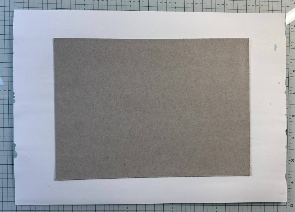 Carton positionné au centre du papier pour fabriquer une couverture d'album photo cartonnée