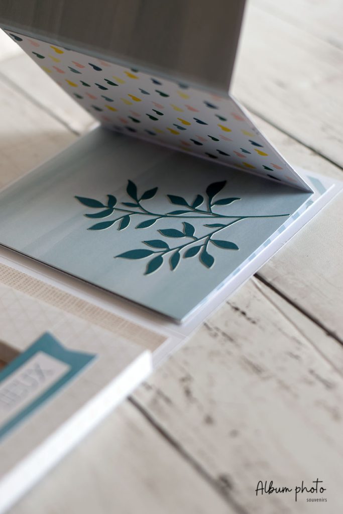 Mini album photo ouvert avec illustration de rameau sur fond bleu
