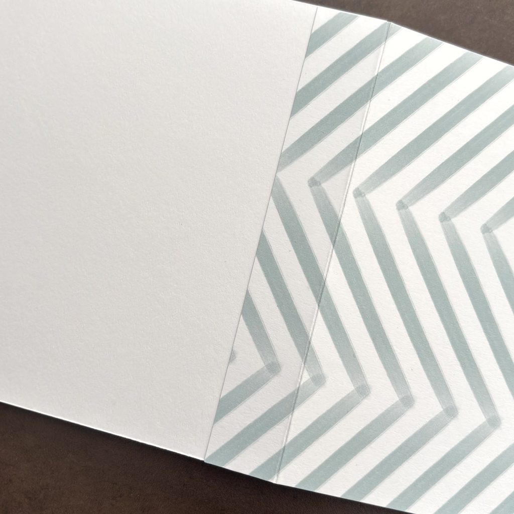 Double page pliée en papier chevron gris et crème pour l'album