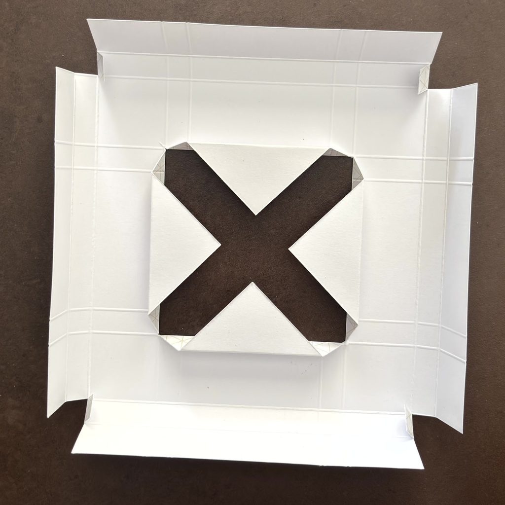 Découpe en X plus affinée sur le cadre en papier blanc