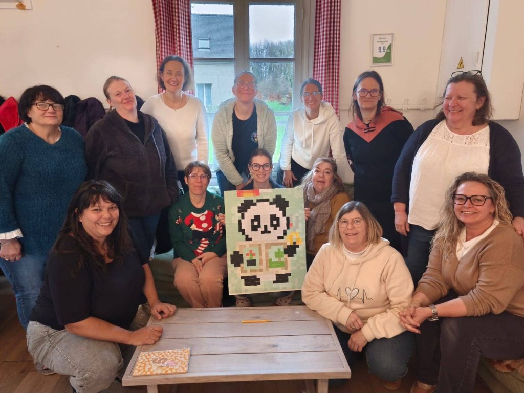 Groupe de participantes du week-end scrapbooking à La Bergerie posant avec une création pixel art en forme de panda