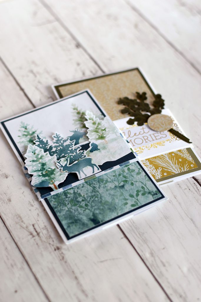Deux cartes cascade fermées posées sur du bois, une version forêt enneigée bleu et vert, une version dorée avec message collect memories