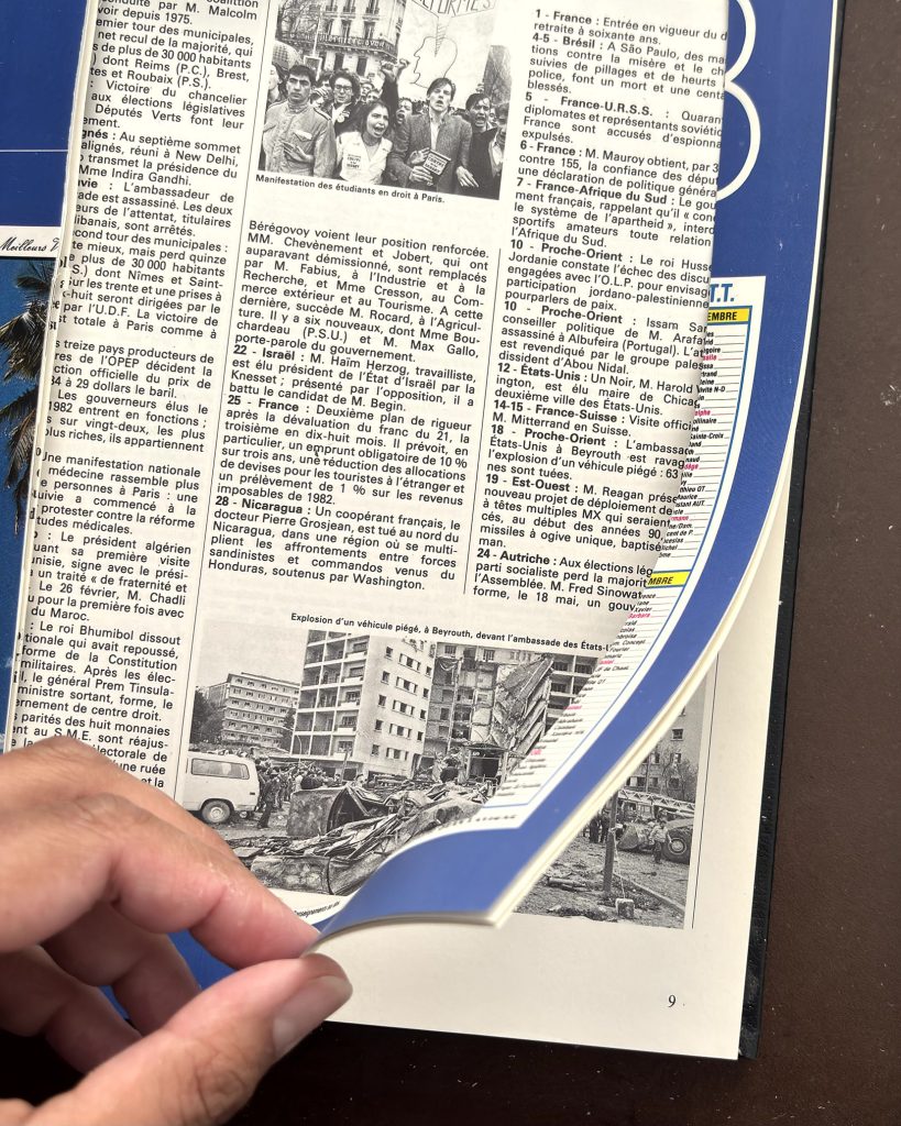 Page du livre ouvert avec article et photos, main soulevant un coin de page